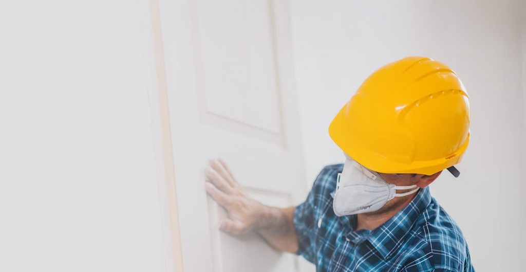 Worker wearing protective gear while sanding drywall