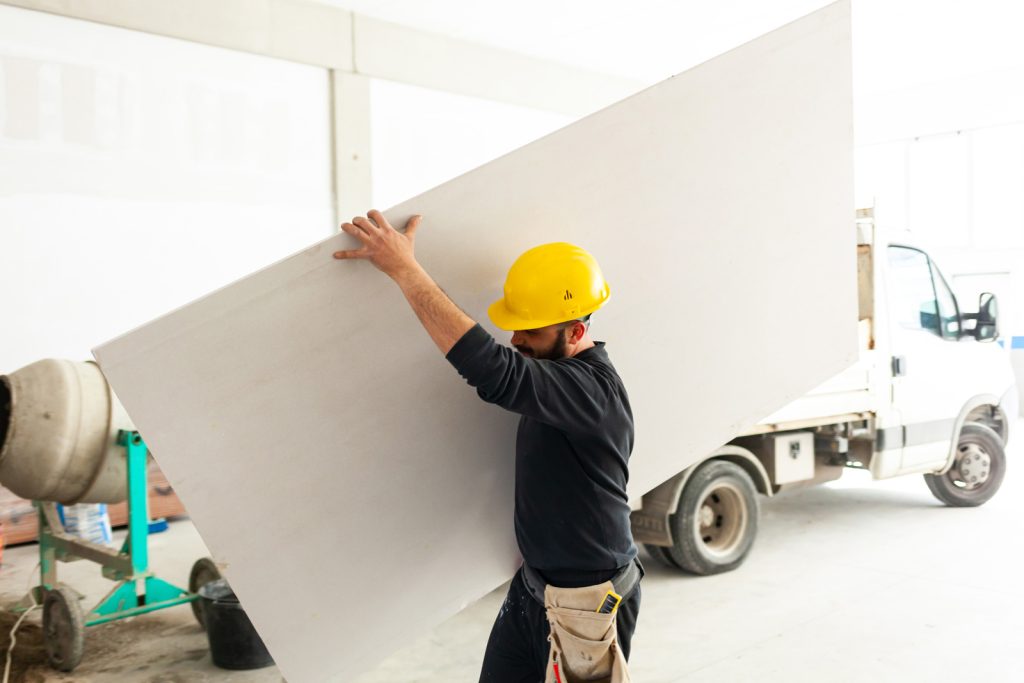 Worker carrying large drywall panel